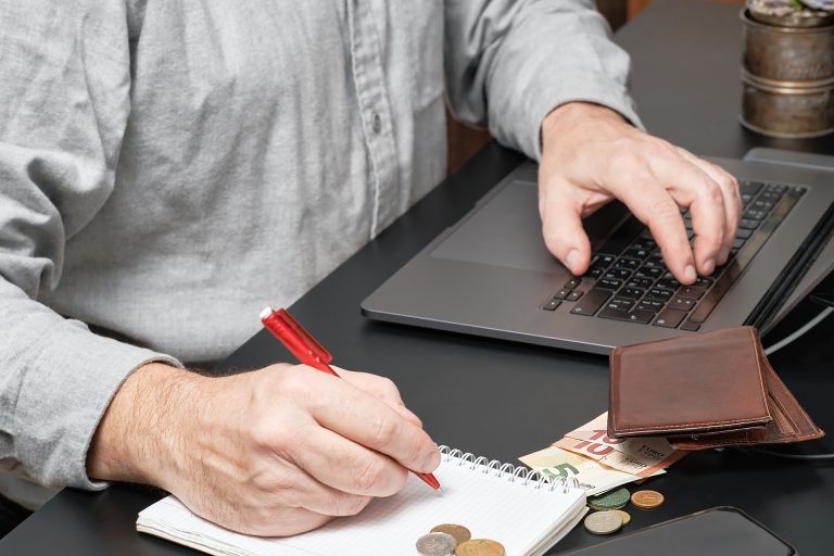 businessman accountant holding pen working desk using laptop calculate financial report 768x512